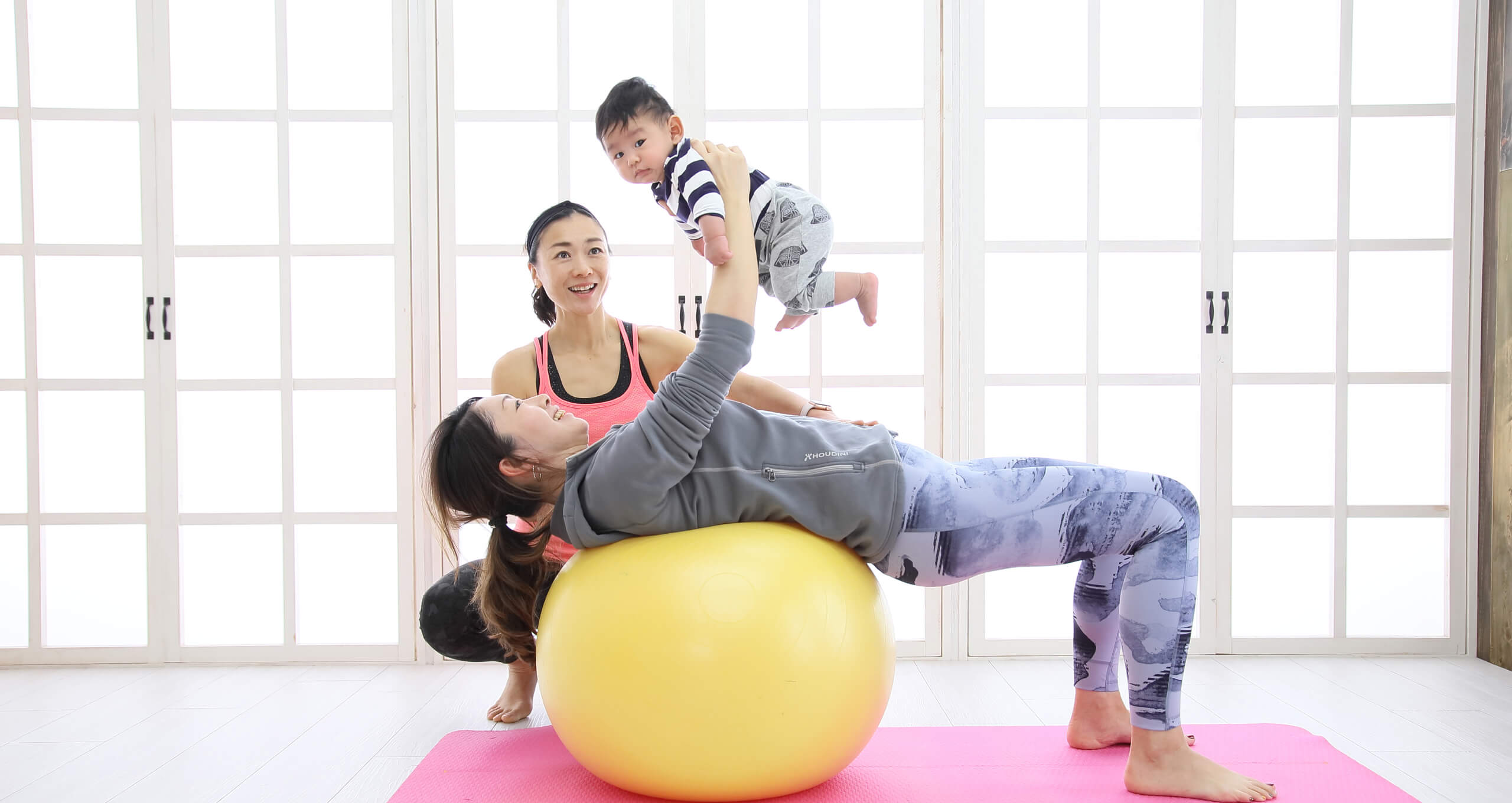 赤ちゃんを抱っこしながらバランスボールトレーニングをしている写真